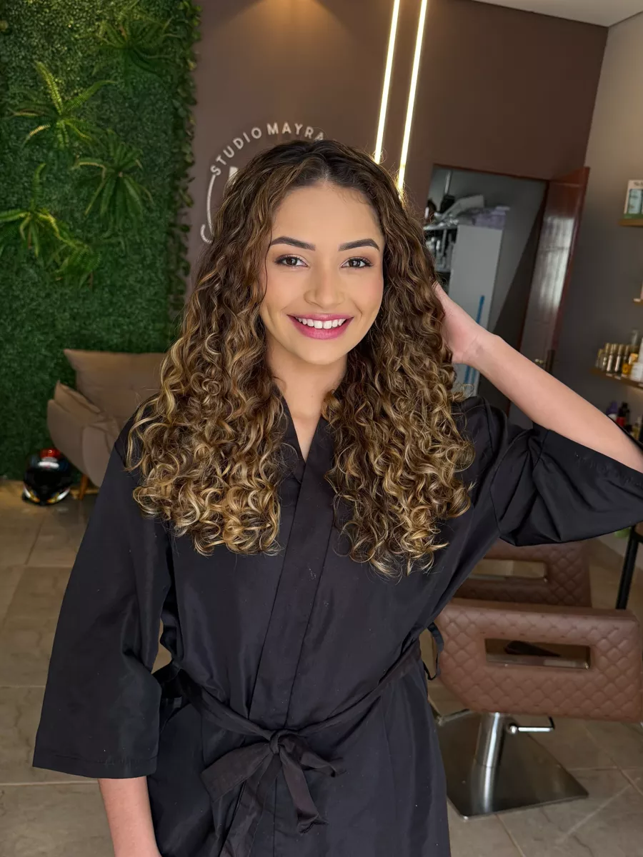 Cliente de cachos dourados volumosos no salão do studio