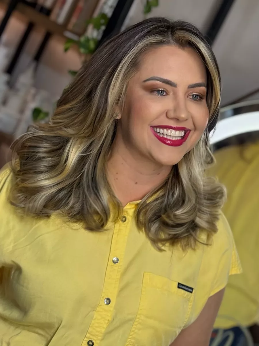 Cliente loira com mechas iluminadas em tom de mel e blusa amarela